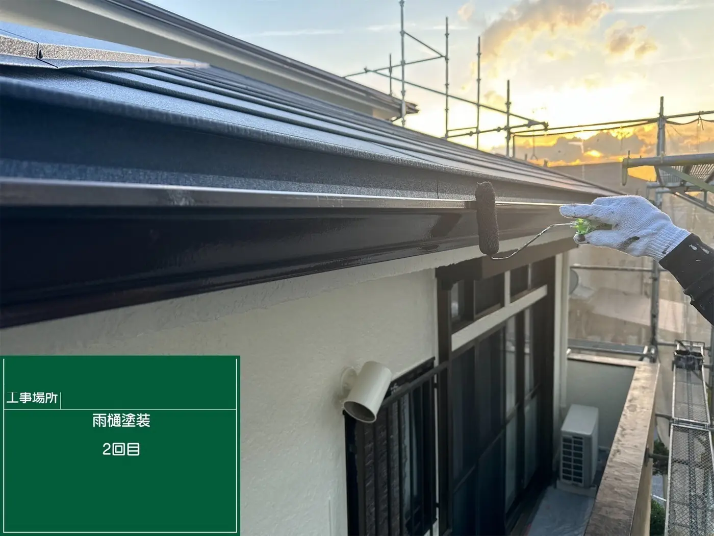 足場を組んだ外壁塗装の現場と夕暮れの空